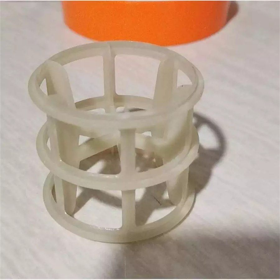 Single semi-transparent white polypropylene Pall ring photographed on a work surface