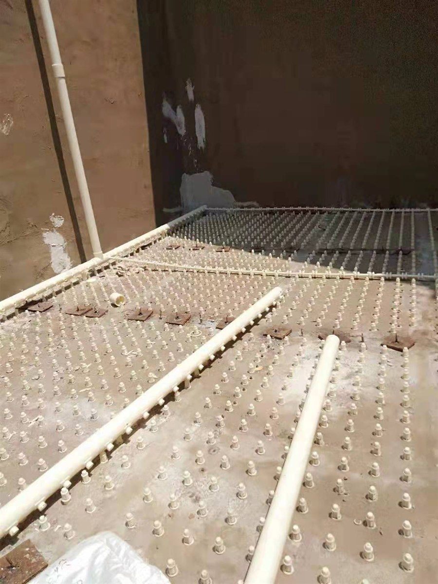 Aerator pipes and distribution nozzles laid over a filter-plate grid in a basin