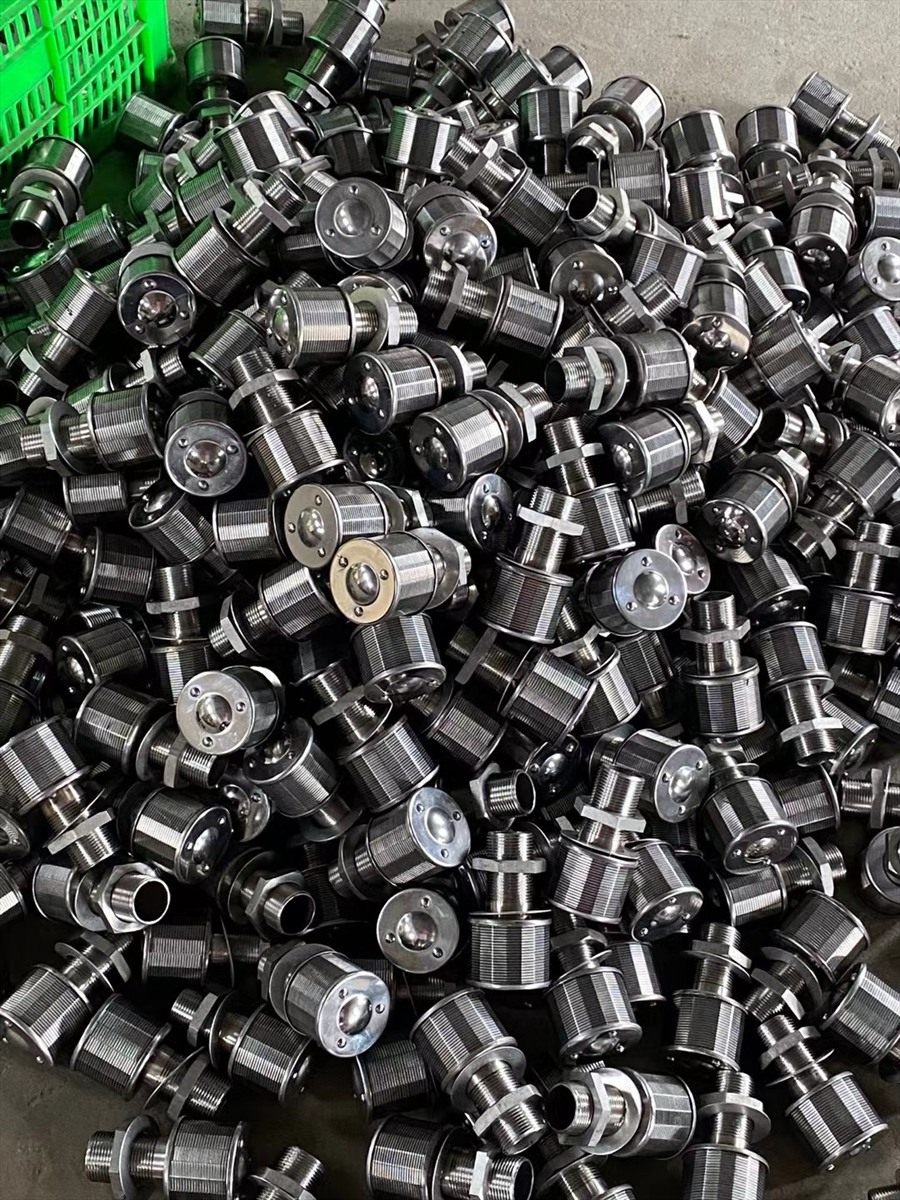 Drain caps in bulk on the workshop floor beside a parts basket