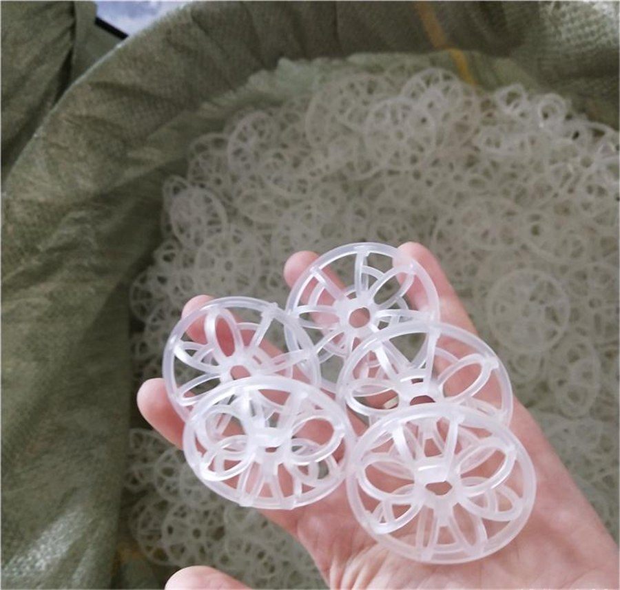 Hand holding several rosette rings above a woven bag full of rings