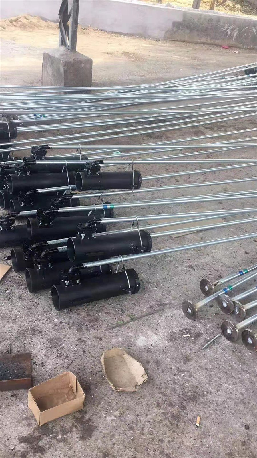 Rows of assembled vortex aerators with long riser pipes staged for dispatch